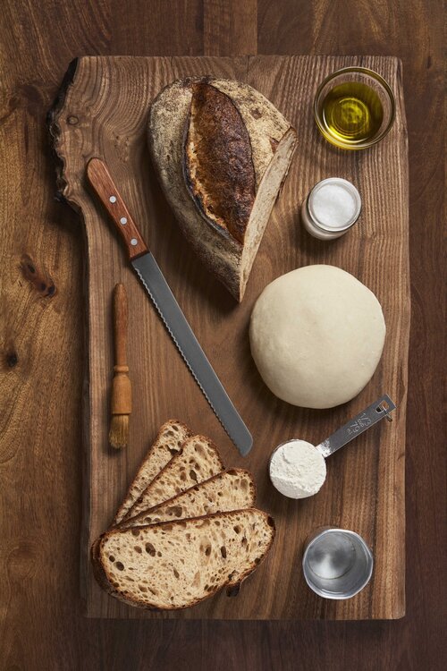 Freshly baked bread with ingredients on cutting board.